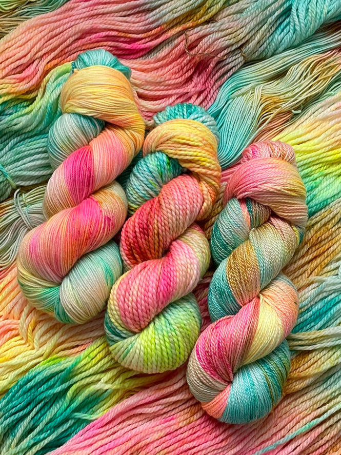Colorful skein of yarn with a gradient of pink, yellow, and blue.