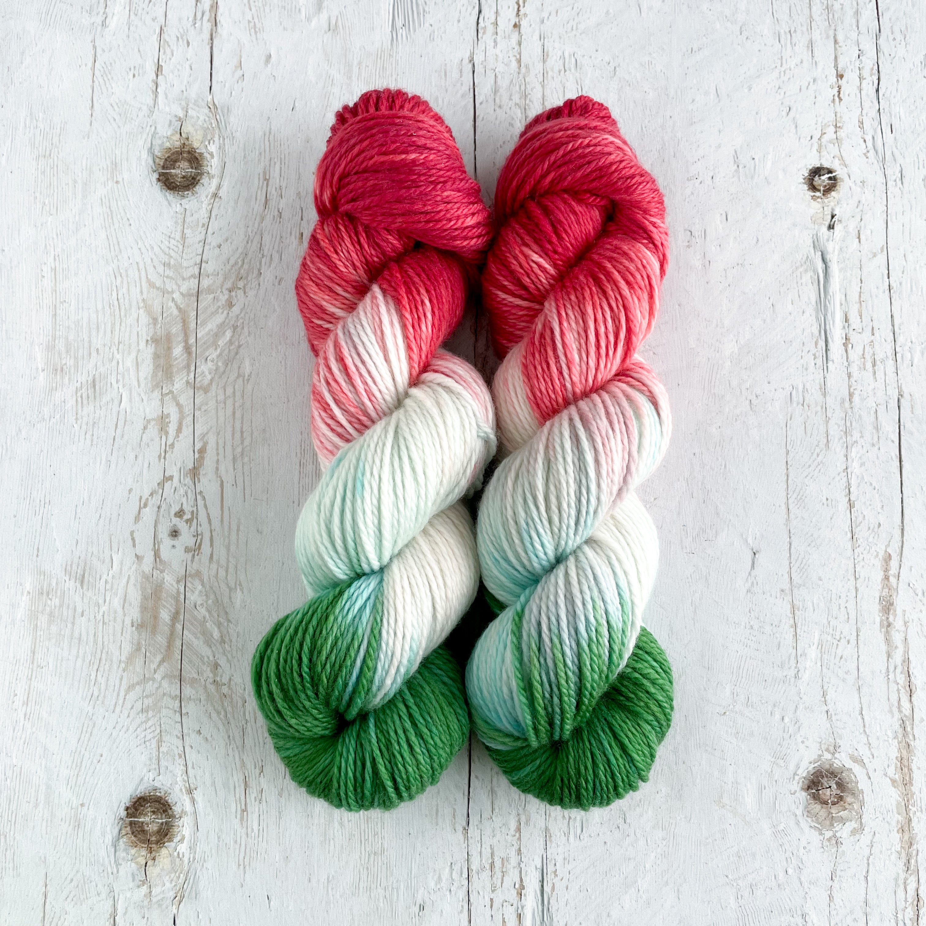 Two hand dyed skeins. Multicolored in Hungarian flag colors. On a wooden surface.