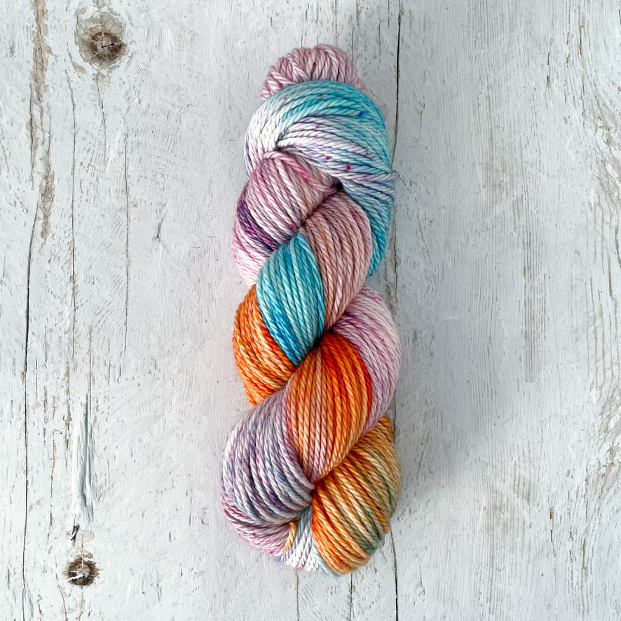 Multicolored skein of hand dyed yarn on a light wooden surface