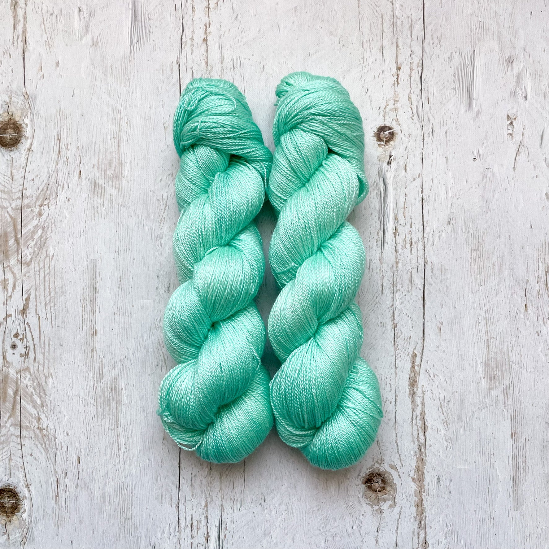 Two skeins of aqua mint yarn on a wooden surface