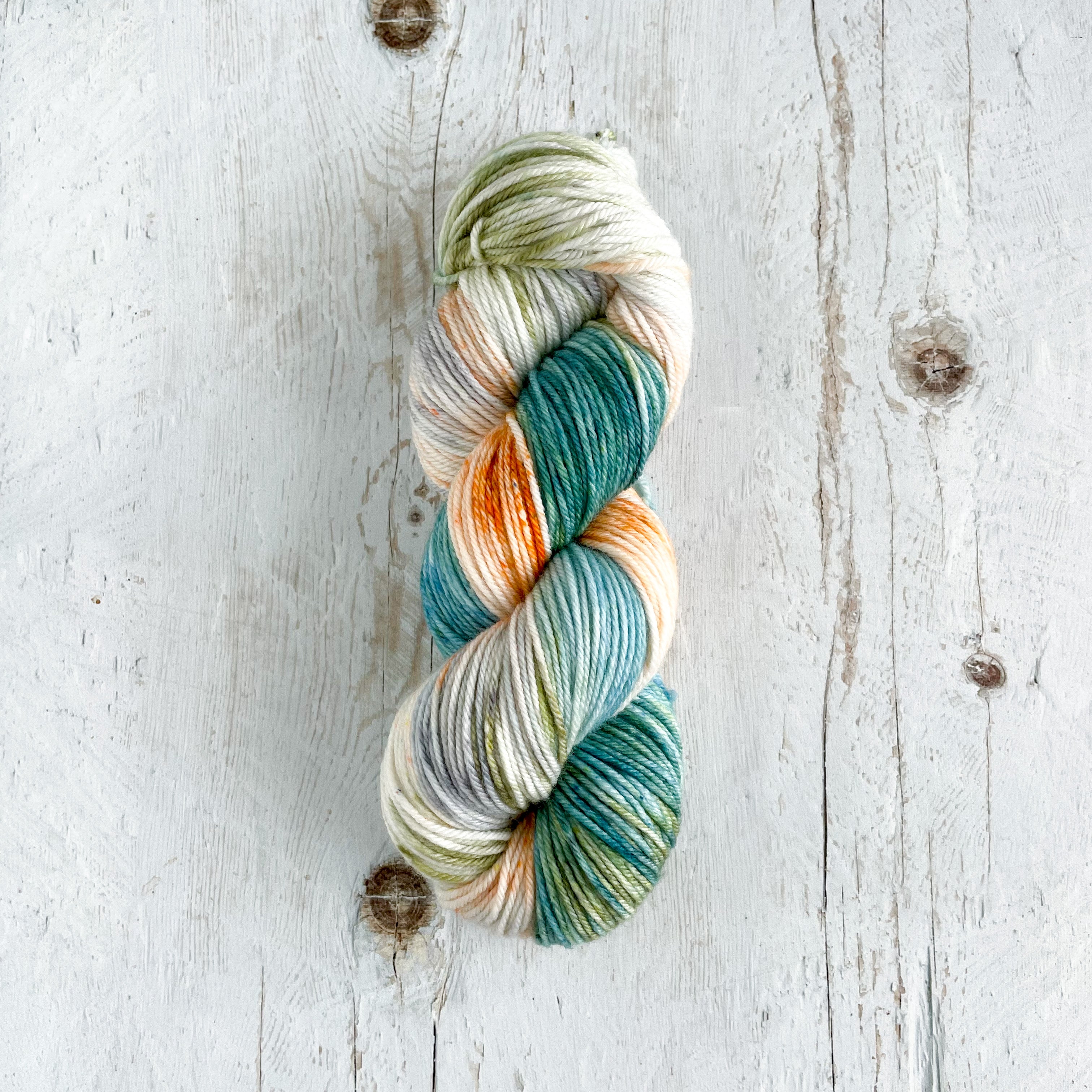 Multicolored skein of hand dyed yarn on a wooden surface