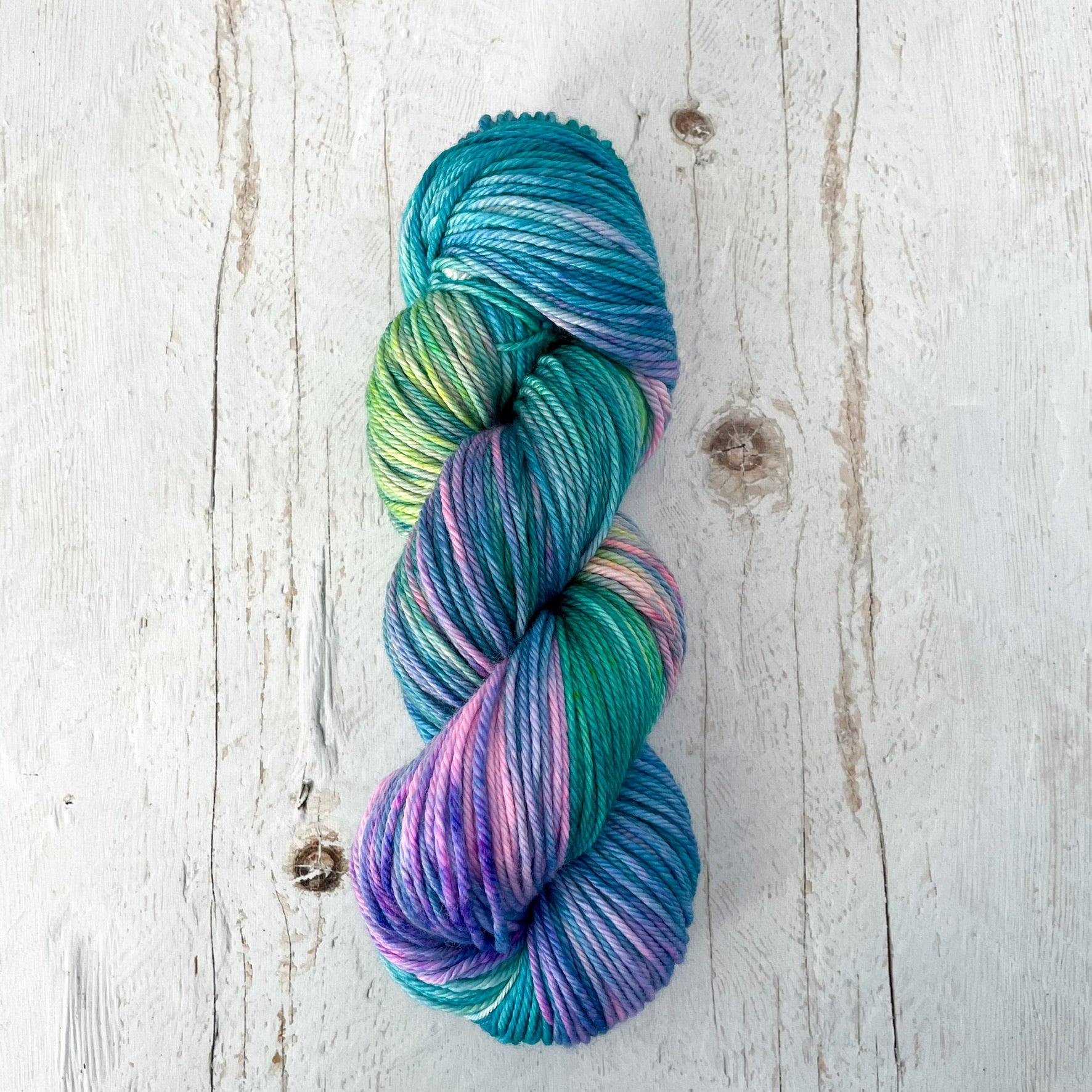 One skein of multicolored hand dyed yarn on a light wooden surface