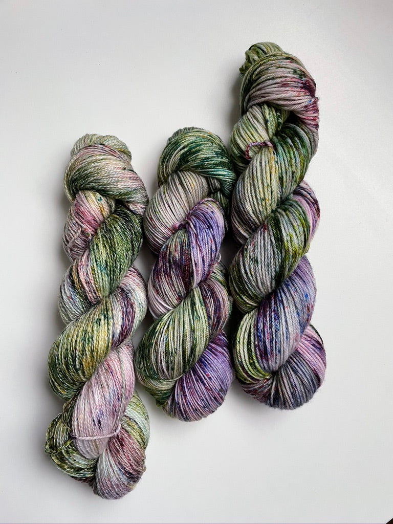 Three skeins of multicolored hand dyed yarn on a white background