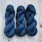 Three skeins of blue yarn on a light wooden surface