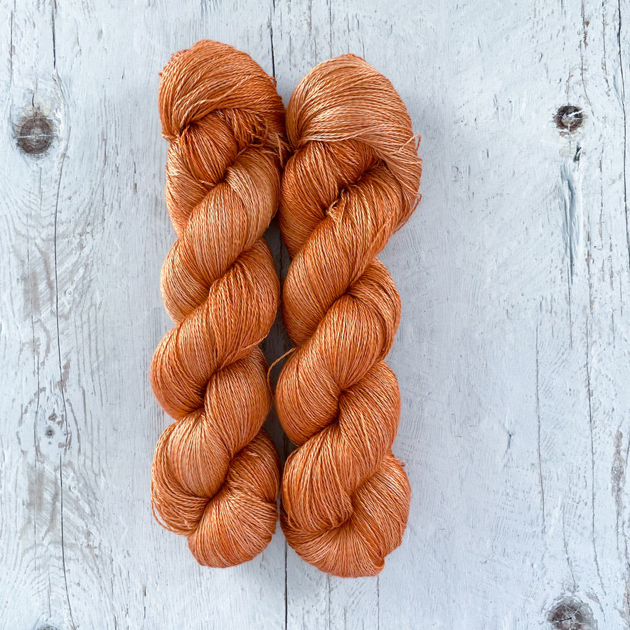Two skeins of caramel yarn on a light wooden surface