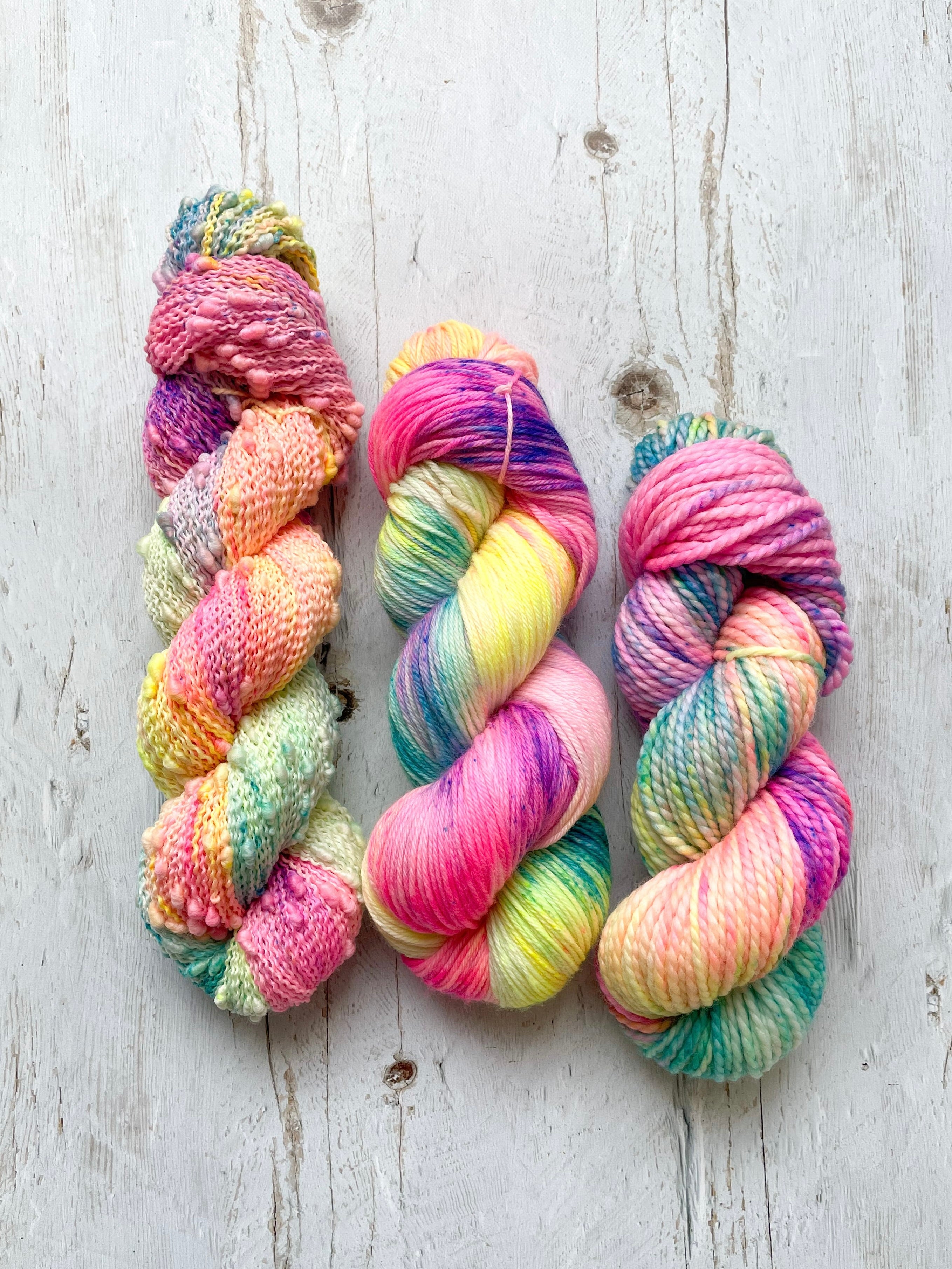 Three skeins of multicolored neon hand dyed yarn on a wooden surface